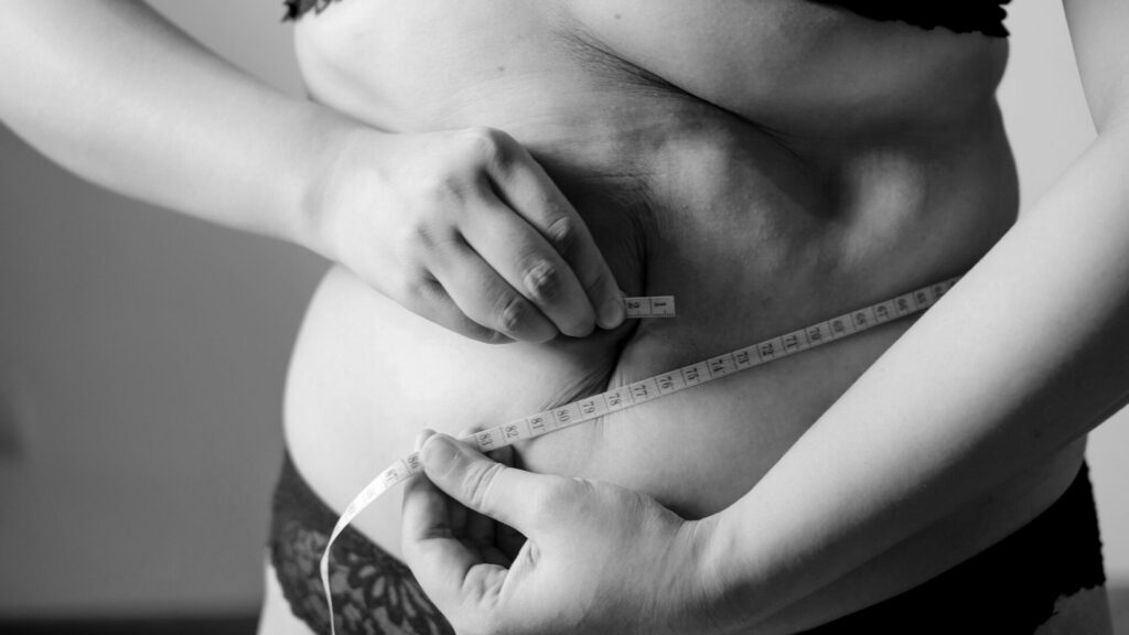 Woman measuring her waist circumference in order to calculate her BRI (Body Roundness Index).